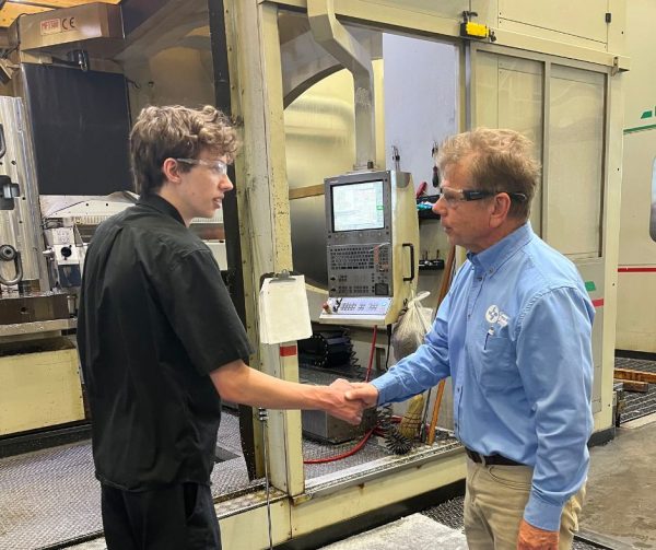 Cavalier Career Ready Participant Nathan shaking hands with Richard Janik in front of a gun drill at Cavalier Tool.