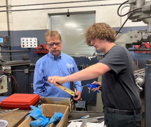 Cavalier Career Ready Participant Logan showing Richard Janik a mold component he worked on in the detail room at Cavalier Tool and Manufacturing.