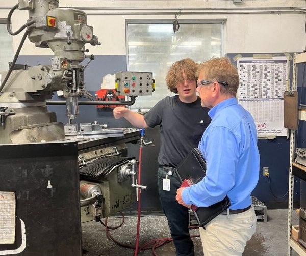 Cavalier Career Ready Participant Logan showing Richard Janik a machine he works on in the detail room at Cavalier Tool and Manufacturing Ltd.