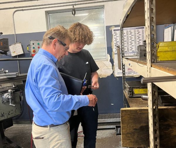 Career Ready Participant Logan shows Richard Janik the tool shelf in the detail room at Cavalier Tool.