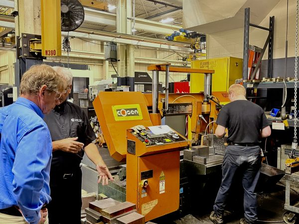 Richard Janik with Cavalier Career Ready participant Cameron. Janik is speaking with Cameron's trainer while Cameron operates a Saw.