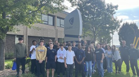 A group photo of Students at Cavalier Tool on Manufacturing Day 2024. They are standing on the front lawn in front of the Cavalier World Headquarters Sign.