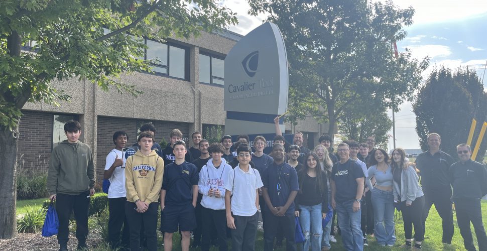 A group photo of Students at Cavalier Tool on Manufacturing Day 2024. They are standing on the front lawn in front of the Cavalier World Headquarters Sign.